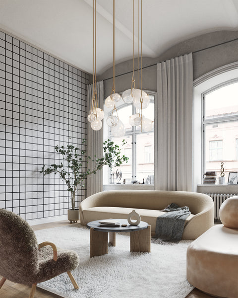 Modern living room with a white grid-patterned wallpaper, curved beige sofa, plush accent chair, and sculptural pendant lighting, creating a contemporary and elegant ambiance.