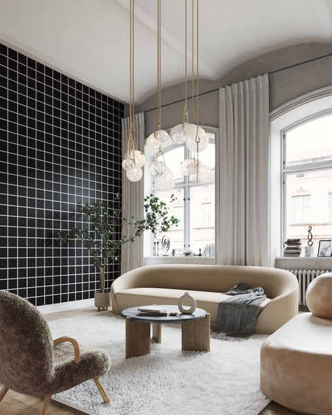 Modern living room with a white and black square grid patterned wallpaper, curved beige sofa, plush accent chair, and sculptural pendant lighting, creating a contemporary and elegant ambiance.