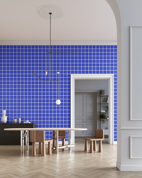 Modern dining room with blue and white square grid patterned wallpaper, a minimalist pendant light, sculptural wooden furniture, and a black sideboard, creating a contemporary and stylish aesthetic.