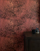 Dramatic botanical wallpaper in a deep rust-red hue with intricate foliage illustrations, styled with a dark wooden cabinet and minimalist decor.