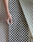 Printed checker board grasscloth wallpaper with woman's hand holding swatches of material