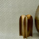 Decorative setup with grasscloth olive green checkered wallpaper covering both the wall and surface, complemented by metallic gold sculptural objects for a modern touch.