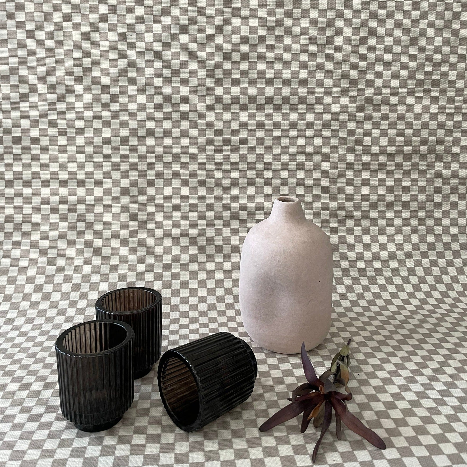 Taupe colored grasscloth wallpaper with vase and three glass candle holders